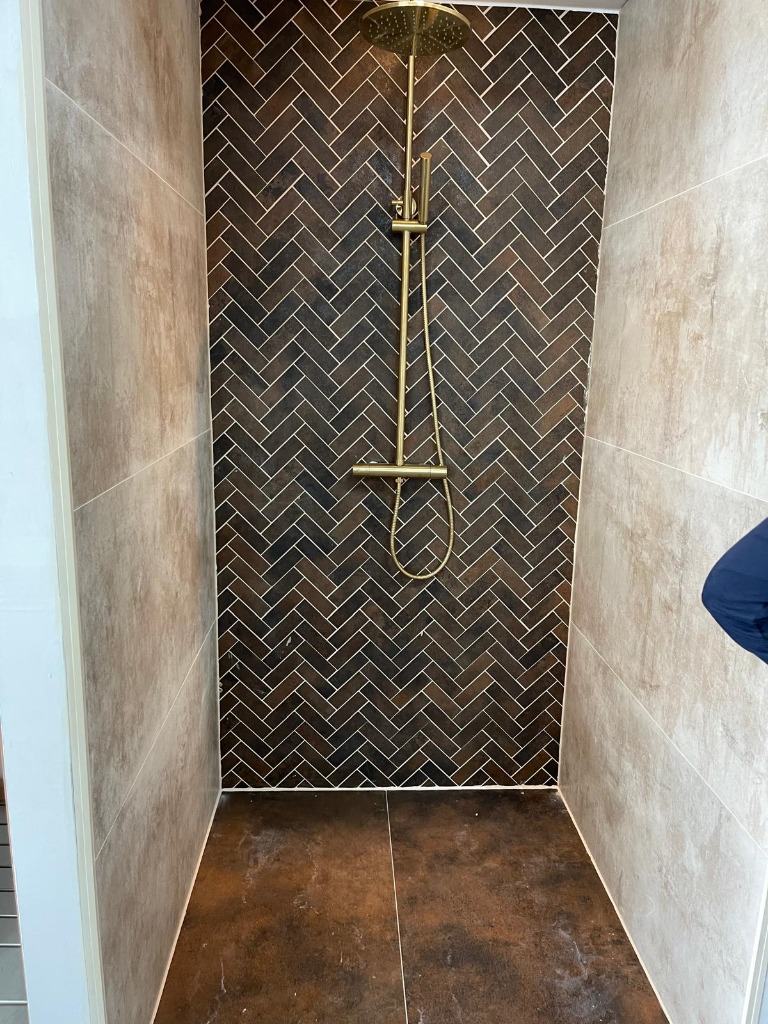 Begehbare Dusche mit Fischgrät-Wandfliesen und Goldarmatur
